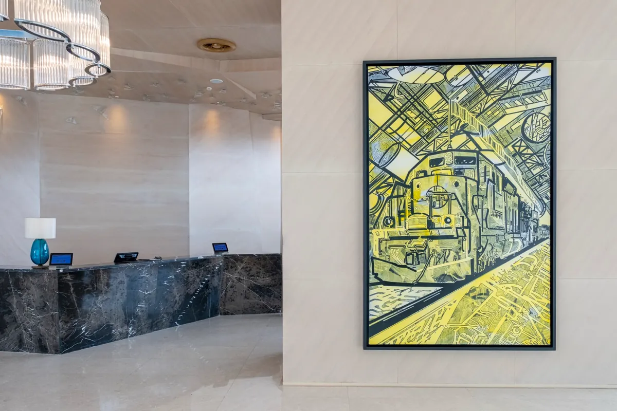 Mermer resepsiyon bankosu ve sarı tonlarda büyük bir tablo bulunan lobi
