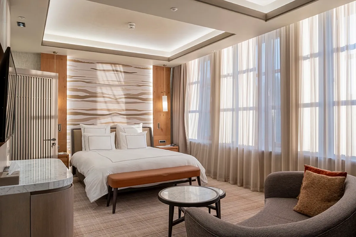 Geniş pencereli otel odasında yatak ve oturma alanı